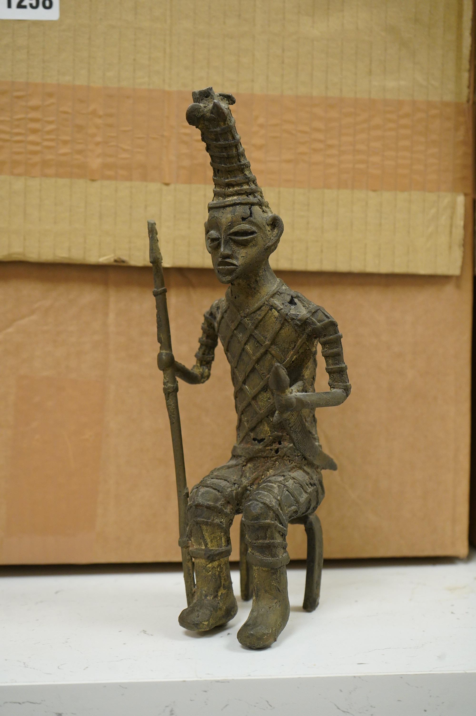 Five ethnographic items; an early 20th century chip carved Australian boomerang-60cm long , together with a later example, a Benin bonds of a warrior seated on a stool, a Makonde African carved figure group and an Africa
